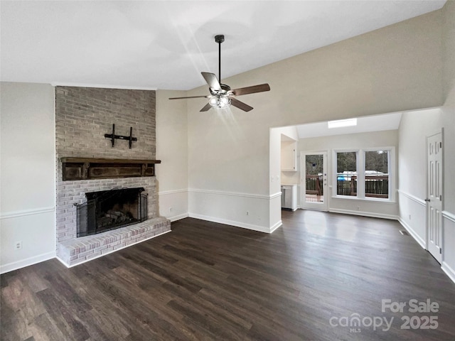 unfurnished living room with dark wood-type flooring, a fireplace, baseboards, ceiling fan, and vaulted ceiling