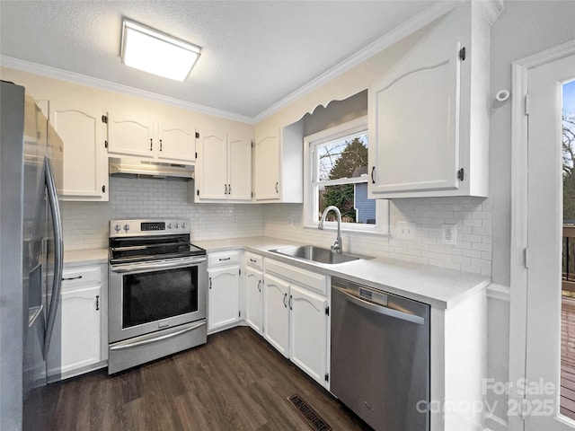 kitchen featuring a sink, under cabinet range hood, ornamental molding, stainless steel appliances, and dark wood-style flooring