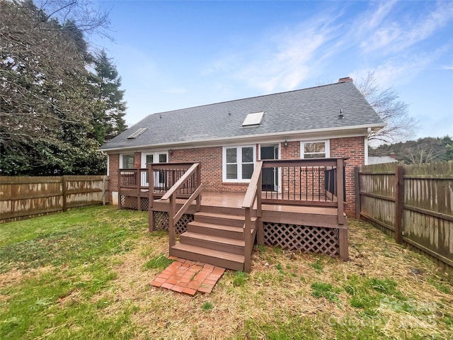 rear view of property featuring brick siding, a fenced backyard, a shingled roof, and a yard