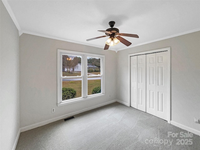 unfurnished bedroom featuring visible vents, baseboards, carpet flooring, and crown molding