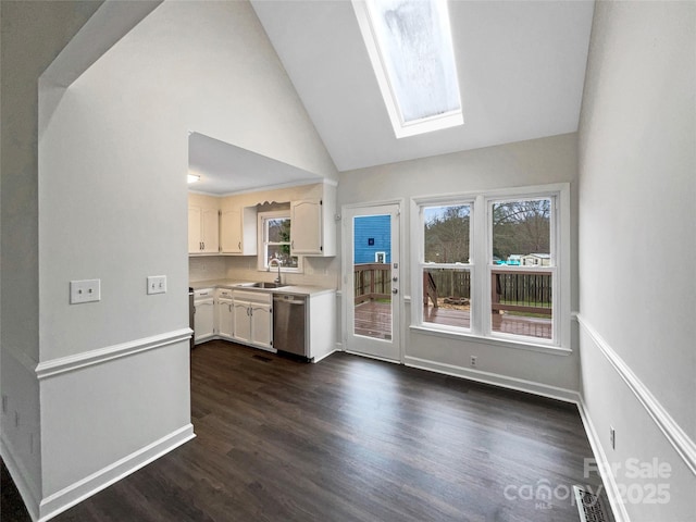 kitchen featuring dishwasher, light countertops, a skylight, white cabinetry, and a sink