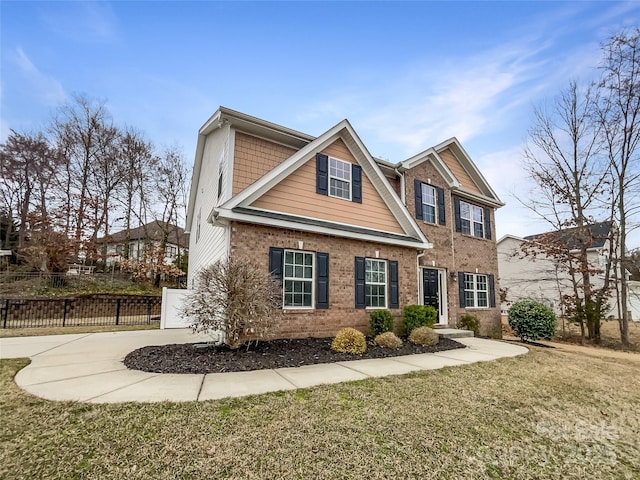 view of front of home with driveway, a gate, a front lawn, fence, and brick siding