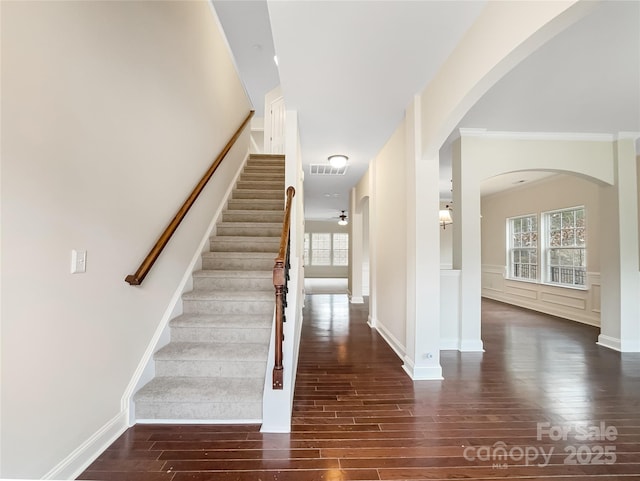 stairs with visible vents, wood finished floors, and wainscoting