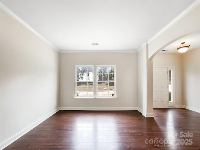 spare room with arched walkways, dark wood-type flooring, baseboards, and ornamental molding