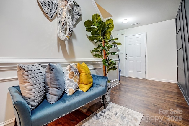 sitting room with wood finished floors, visible vents, and baseboards