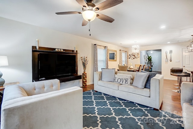 living room with recessed lighting, baseboards, wood finished floors, and ceiling fan with notable chandelier