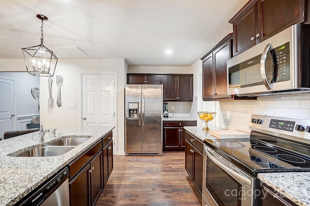 kitchen with dark wood-style floors, light stone countertops, a sink, stainless steel appliances, and dark brown cabinets