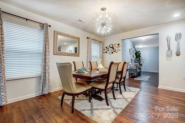 dining area featuring a notable chandelier, visible vents, baseboards, and wood finished floors