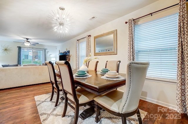 dining room with visible vents, ceiling fan with notable chandelier, baseboards, and wood finished floors