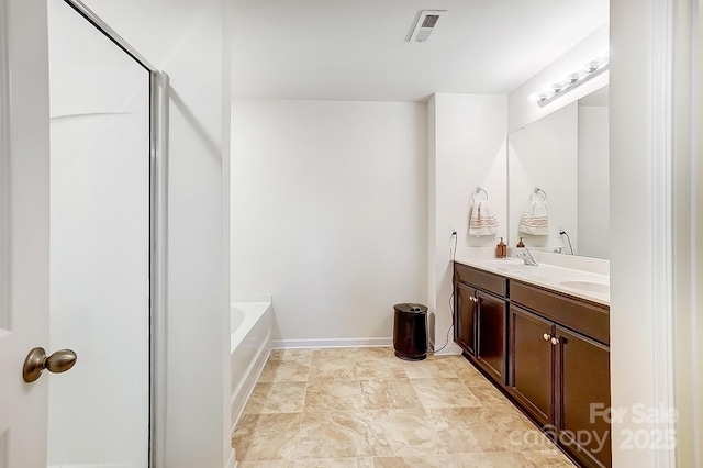 bathroom featuring visible vents, baseboards, double vanity, a sink, and a garden tub