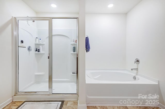 bathroom with a stall shower and a garden tub