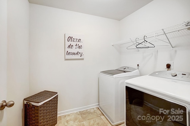 laundry area with laundry area, washing machine and dryer, and baseboards