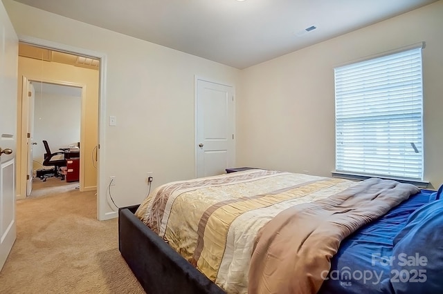 bedroom with visible vents, light colored carpet, and attic access