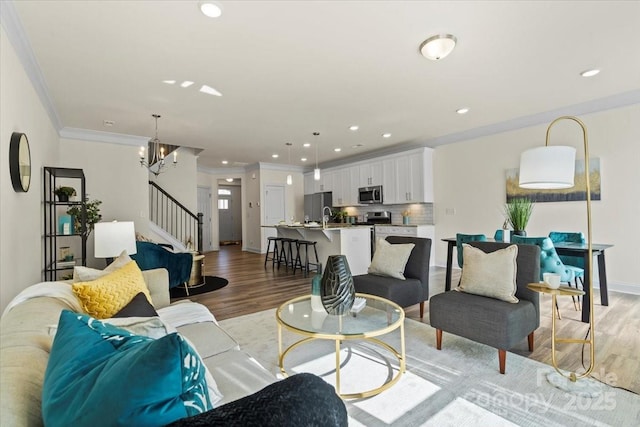 living room with stairs, crown molding, light wood-style flooring, and recessed lighting