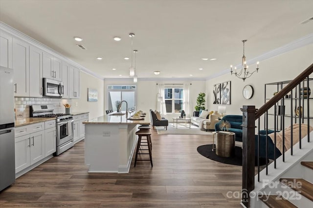 kitchen with dark wood-style floors, appliances with stainless steel finishes, and ornamental molding