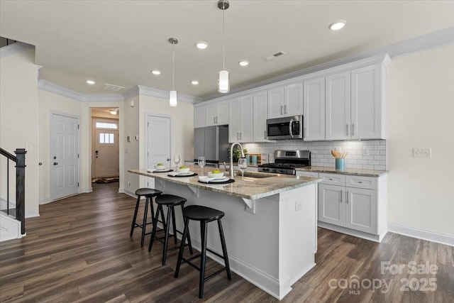 kitchen featuring tasteful backsplash, crown molding, an island with sink, stainless steel appliances, and a sink