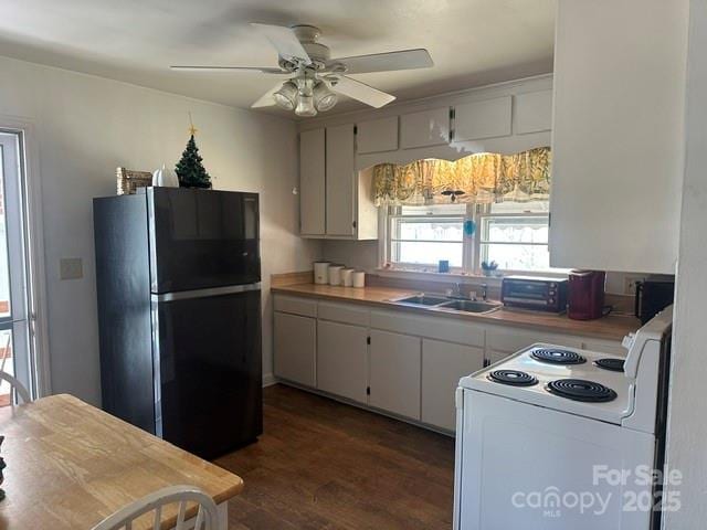 kitchen featuring electric stove, a sink, freestanding refrigerator, light countertops, and dark wood-style flooring