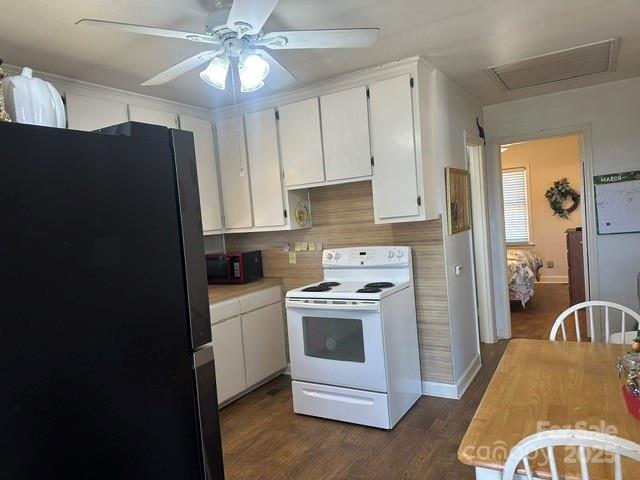 kitchen with light countertops, freestanding refrigerator, white electric stove, white cabinetry, and dark wood-style flooring