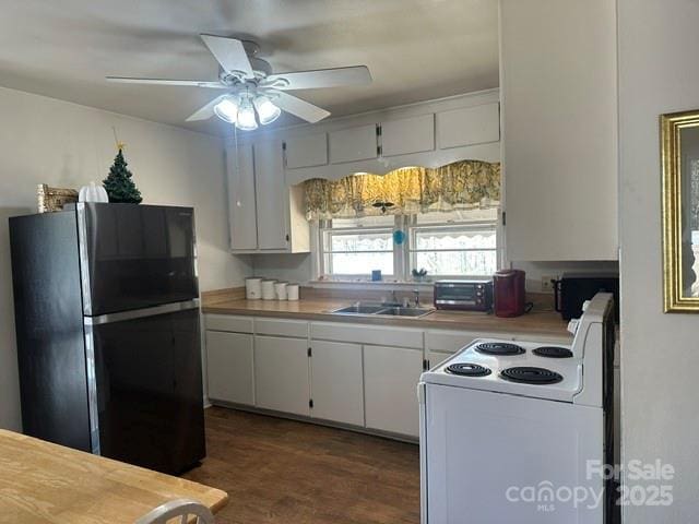 kitchen with a sink, light countertops, freestanding refrigerator, and white electric range oven