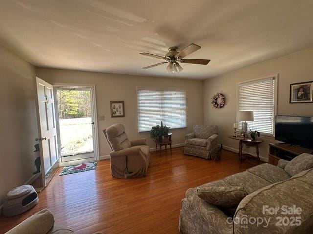 living room featuring ceiling fan, baseboards, and wood finished floors