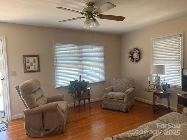 sitting room with baseboards, a ceiling fan, and wood finished floors