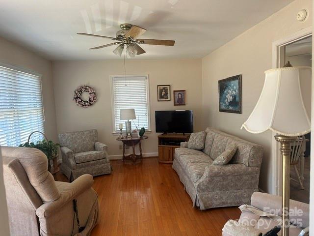 living room featuring a ceiling fan, wood finished floors, and baseboards