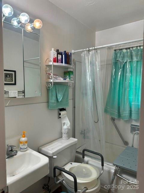 bathroom with toilet, shower / bath combo, and a sink