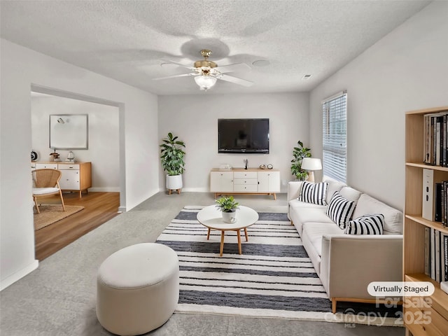 living area featuring baseboards, a textured ceiling, and ceiling fan