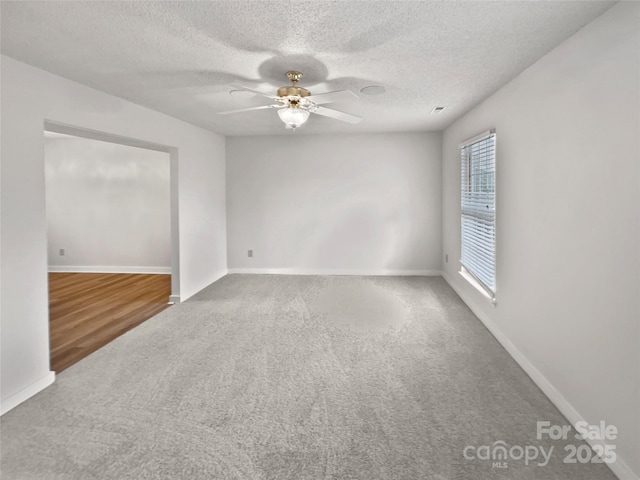 carpeted spare room with baseboards, a textured ceiling, and ceiling fan