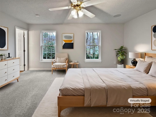 carpeted bedroom with baseboards, multiple windows, a textured ceiling, and a ceiling fan