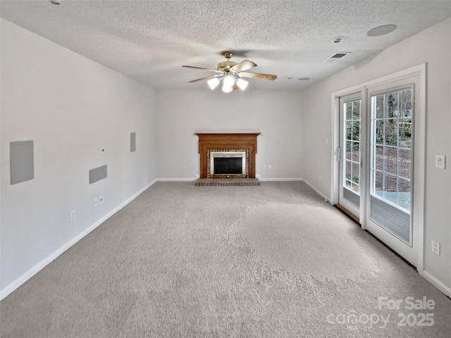 unfurnished living room with visible vents, a ceiling fan, a fireplace, carpet flooring, and baseboards