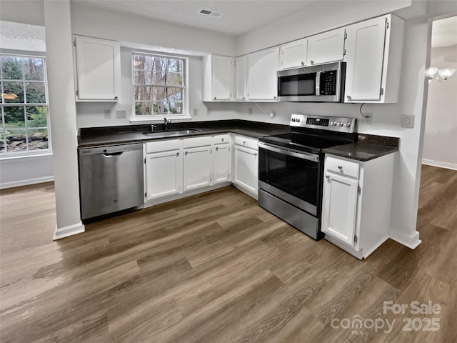 kitchen with white cabinets, visible vents, appliances with stainless steel finishes, and a sink