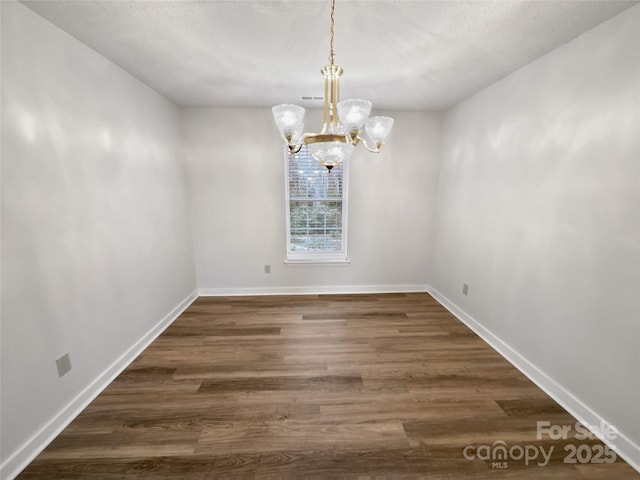 unfurnished dining area with visible vents, baseboards, an inviting chandelier, and dark wood-style flooring