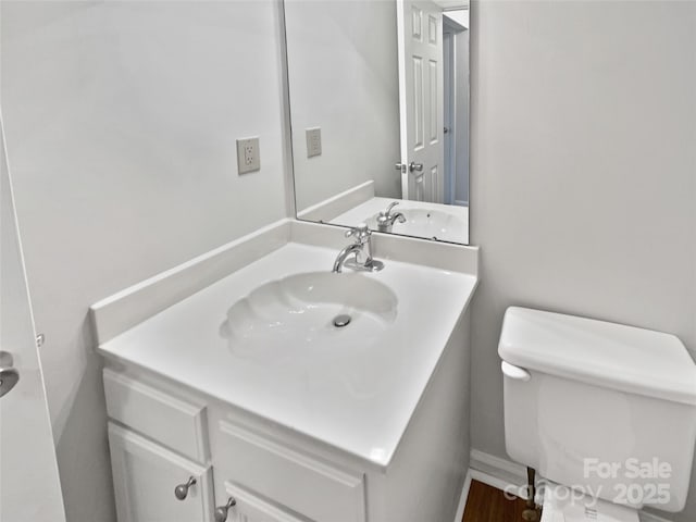 half bath featuring toilet, vanity, and wood finished floors