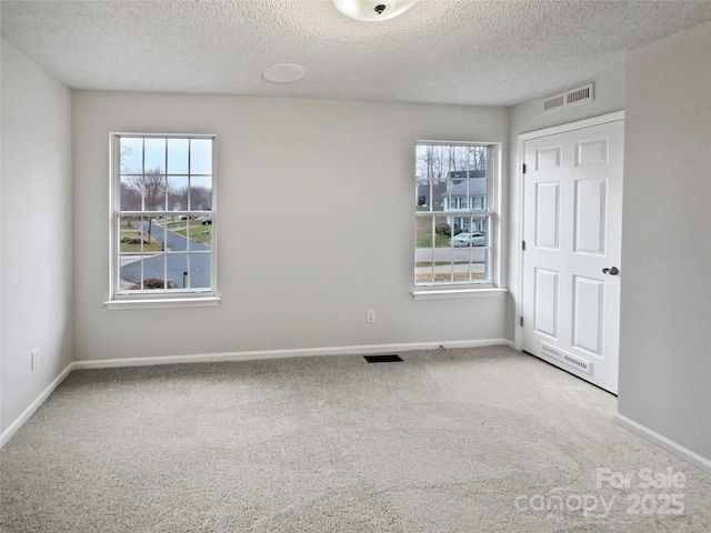 unfurnished bedroom with visible vents, multiple windows, and carpet