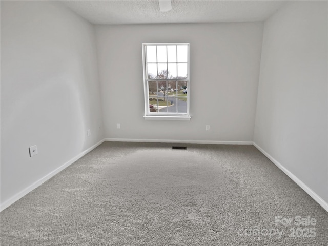 empty room featuring baseboards, visible vents, carpet floors, and a textured ceiling