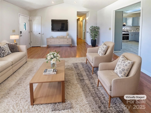 living room featuring baseboards, wood finished floors, and vaulted ceiling