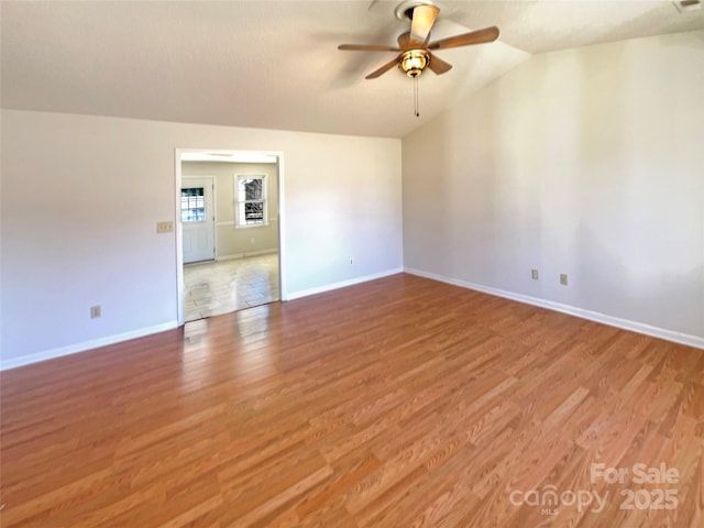 empty room with light wood finished floors, baseboards, lofted ceiling, and ceiling fan