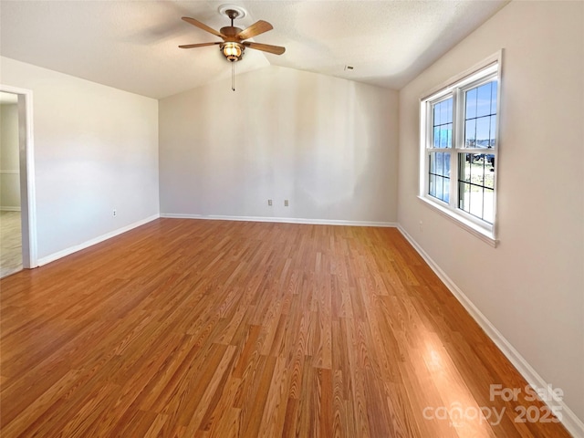 unfurnished room with lofted ceiling, baseboards, light wood finished floors, and ceiling fan