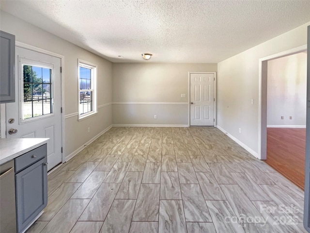 unfurnished room featuring a textured ceiling, light wood-type flooring, and baseboards