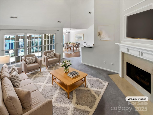 living area with a fireplace, visible vents, carpet floors, and baseboards