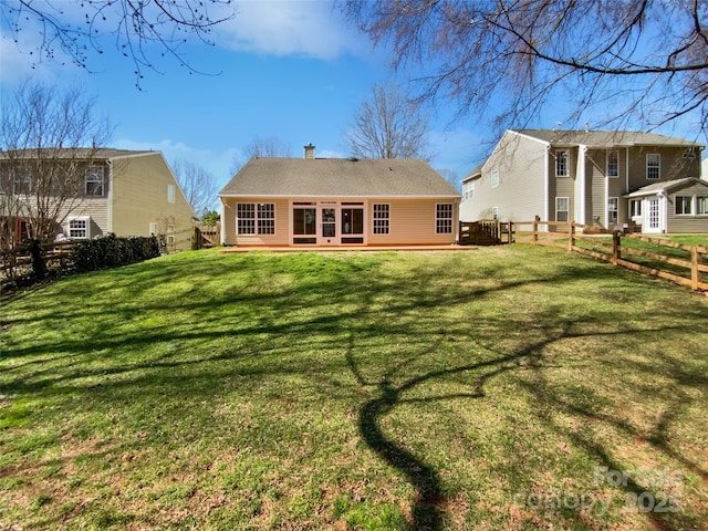 rear view of property with a yard, a fenced backyard, and a chimney