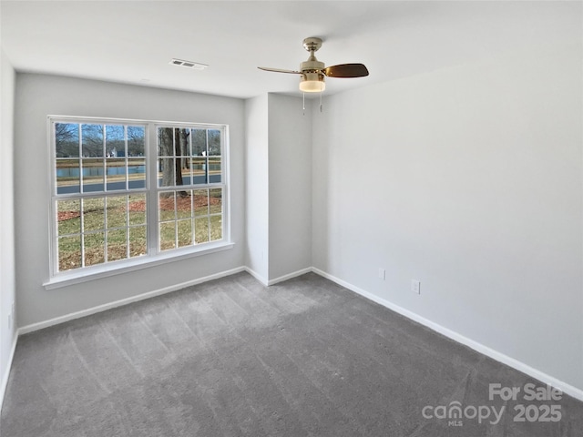 spare room with visible vents, plenty of natural light, carpet, and baseboards