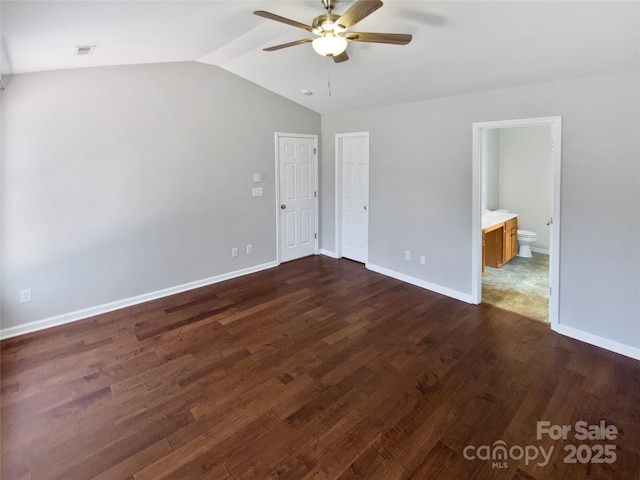 unfurnished bedroom with dark wood finished floors, connected bathroom, baseboards, ceiling fan, and vaulted ceiling