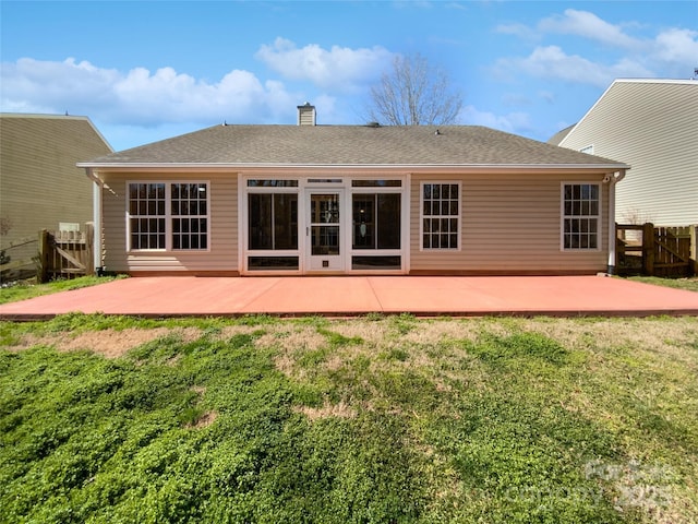 rear view of property with a yard, a chimney, a patio, and fence