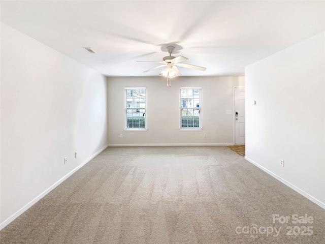 spare room featuring visible vents, light colored carpet, baseboards, and ceiling fan