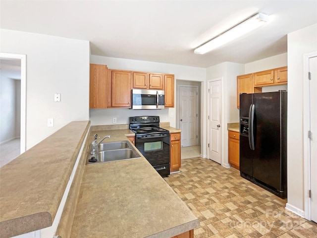 kitchen with a peninsula, black appliances, light countertops, and a sink