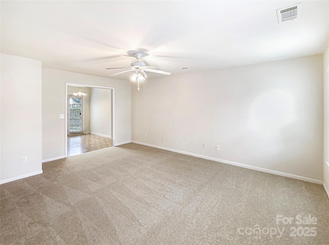 carpeted empty room with a ceiling fan, visible vents, and baseboards