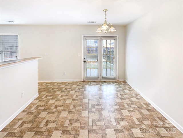 spare room featuring visible vents, baseboards, and a chandelier