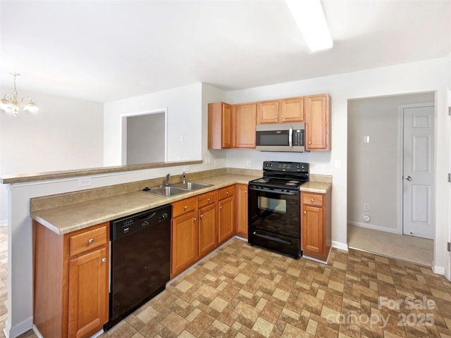 kitchen featuring a peninsula, a sink, black appliances, light countertops, and a notable chandelier